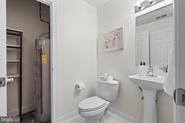 bathroom with water heater, tile patterned flooring, and toilet