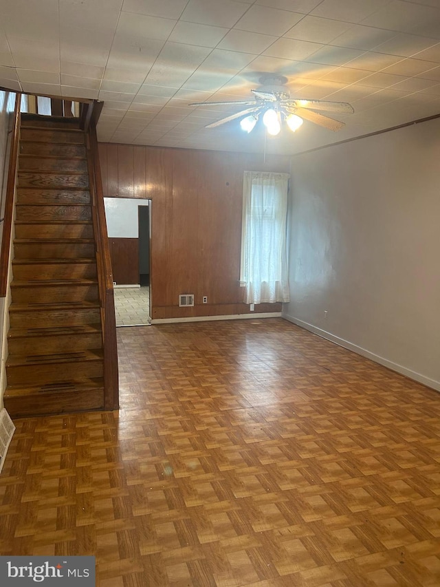 spare room featuring light parquet flooring, ceiling fan, and wood walls