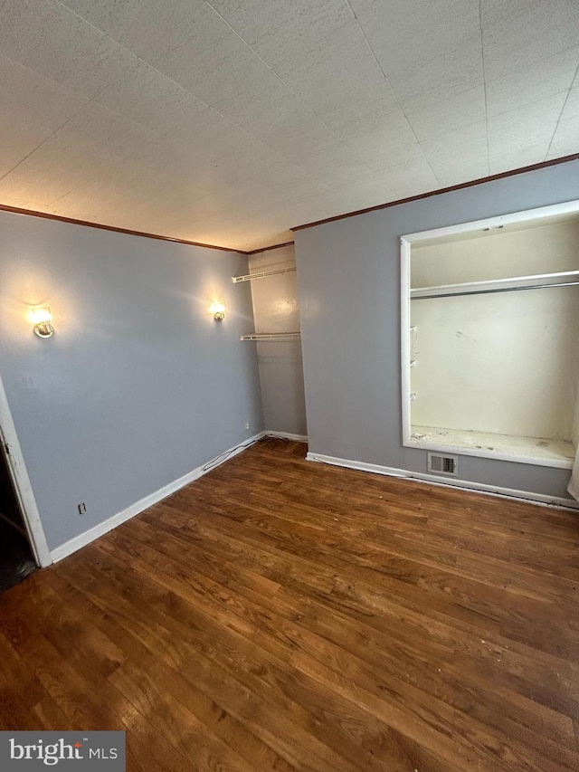 empty room featuring crown molding and dark wood-type flooring