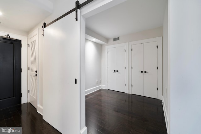 hallway featuring a barn door and dark hardwood / wood-style floors