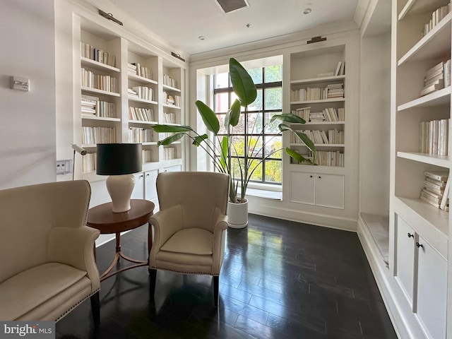 sitting room with built in shelves and dark hardwood / wood-style flooring