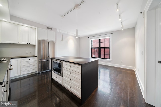 kitchen featuring dark hardwood / wood-style floors, white cabinets, stainless steel appliances, and decorative light fixtures