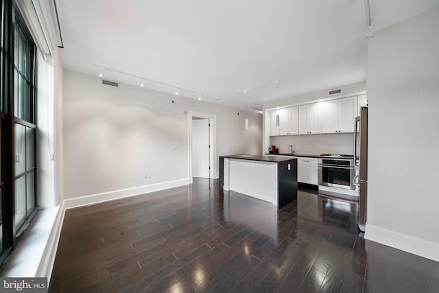 kitchen featuring white cabinetry, sink, dark wood-type flooring, stainless steel appliances, and tasteful backsplash