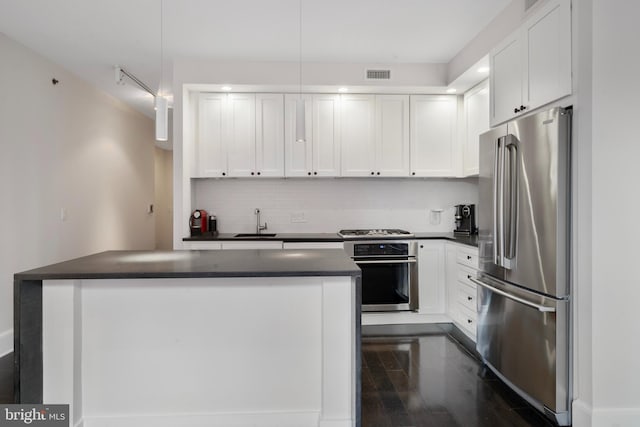 kitchen with pendant lighting, backsplash, white cabinets, sink, and appliances with stainless steel finishes