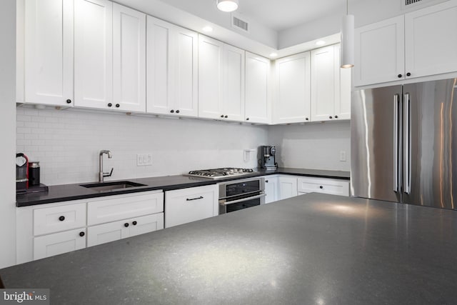 kitchen with white cabinets, appliances with stainless steel finishes, decorative backsplash, and sink