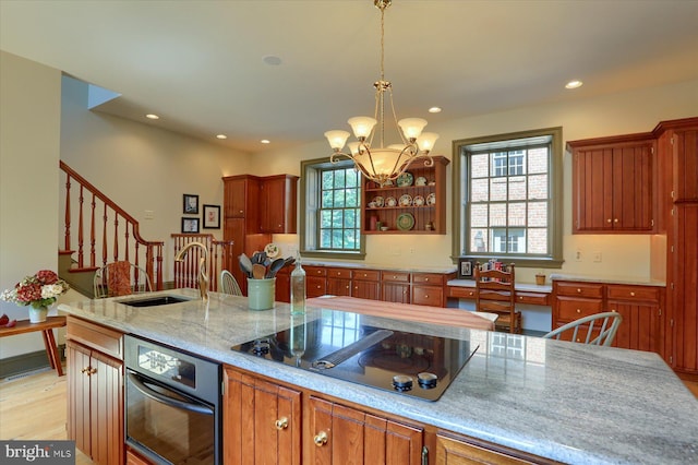 kitchen with a breakfast bar, black electric stovetop, sink, hanging light fixtures, and a notable chandelier