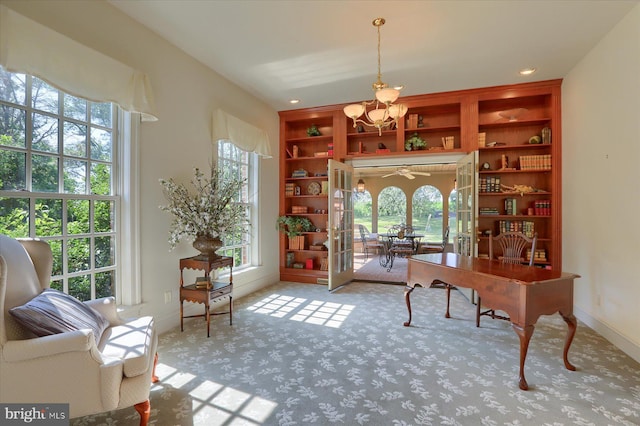 carpeted home office featuring built in shelves and a chandelier