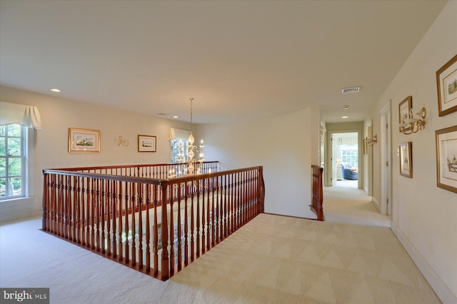 corridor with a chandelier and light colored carpet