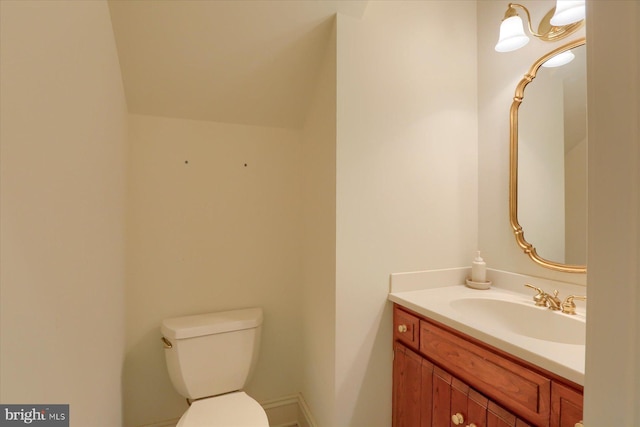 bathroom featuring vanity, toilet, and lofted ceiling