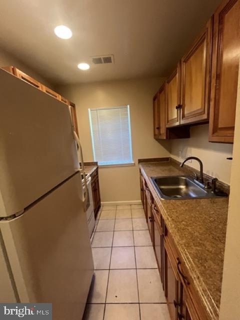 kitchen with stainless steel fridge, sink, light tile patterned flooring, and range