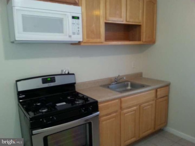 kitchen with light brown cabinetry, stainless steel range with gas cooktop, sink, and light tile patterned floors