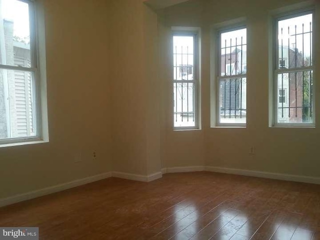 unfurnished room featuring dark hardwood / wood-style flooring and a healthy amount of sunlight