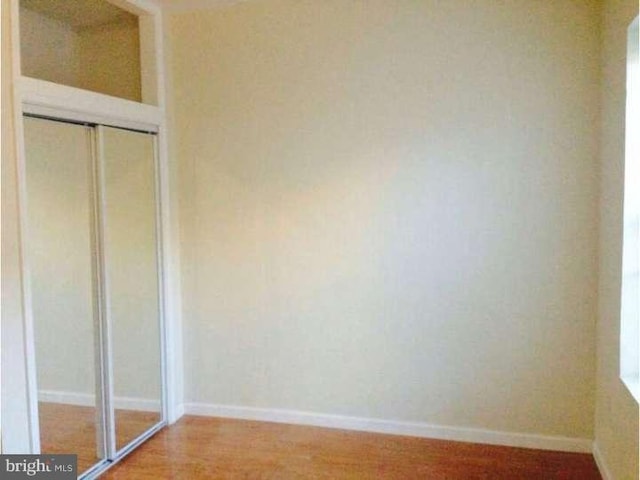 unfurnished bedroom with hardwood / wood-style flooring and a closet