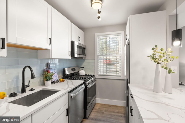 kitchen featuring pendant lighting, white cabinets, sink, light stone counters, and stainless steel appliances