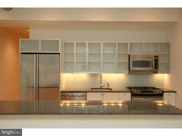 kitchen with dark stone countertops, sink, appliances with stainless steel finishes, and tasteful backsplash