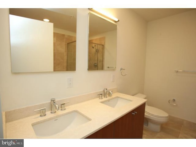 bathroom featuring a shower with door, vanity, toilet, and tile patterned flooring