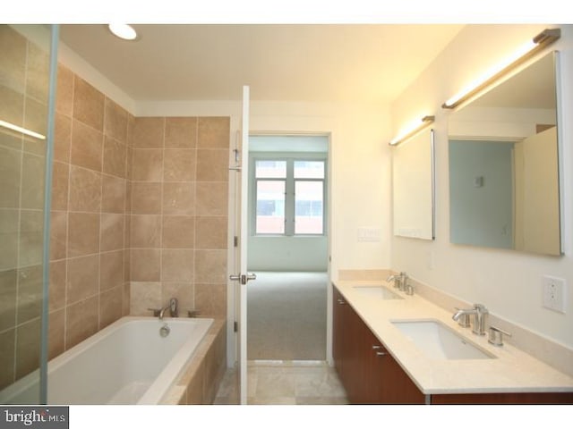 bathroom with tile patterned flooring, vanity, and tiled tub