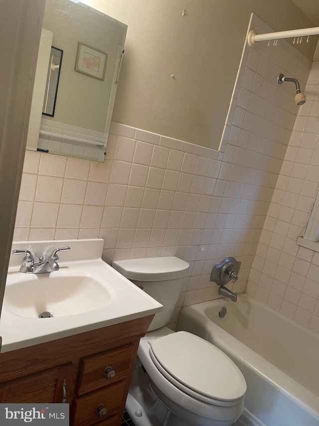 full bathroom featuring vanity, tiled shower / bath combo, tile walls, and toilet