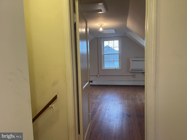 additional living space with an AC wall unit, dark hardwood / wood-style flooring, vaulted ceiling, and baseboard heating