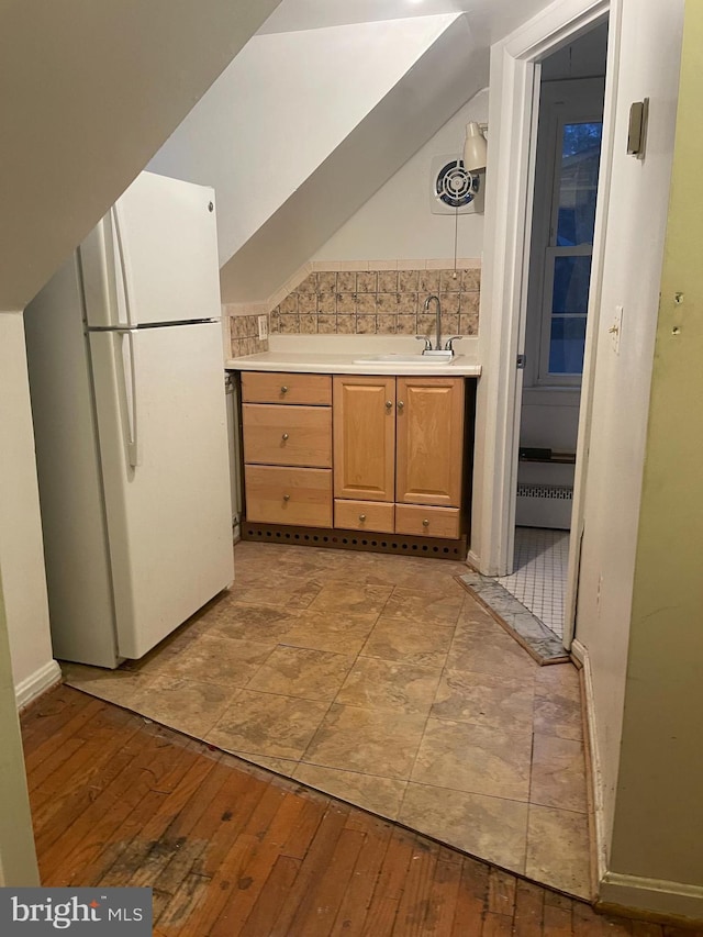 kitchen with decorative backsplash, white fridge, light hardwood / wood-style floors, and sink