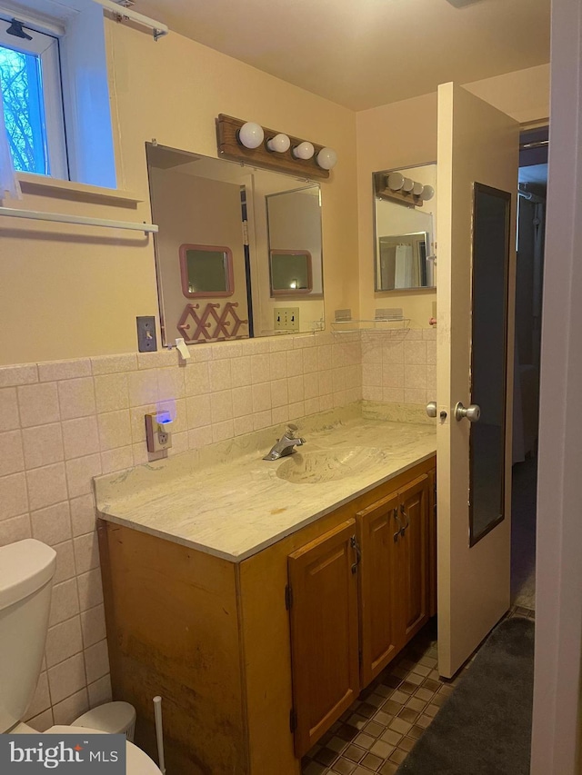 bathroom with vanity, tile walls, and toilet