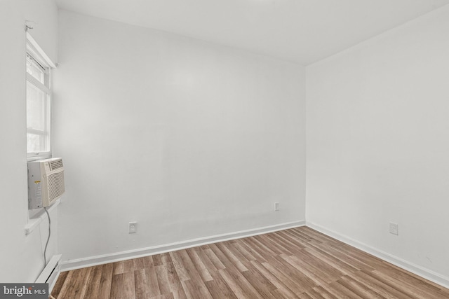 empty room featuring baseboard heating and hardwood / wood-style floors