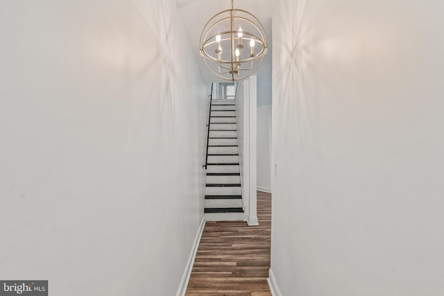 staircase with hardwood / wood-style floors and a chandelier