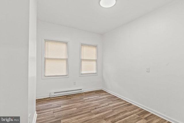 unfurnished room featuring baseboard heating and light hardwood / wood-style flooring