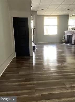 unfurnished living room with a fireplace, a paneled ceiling, and dark hardwood / wood-style floors