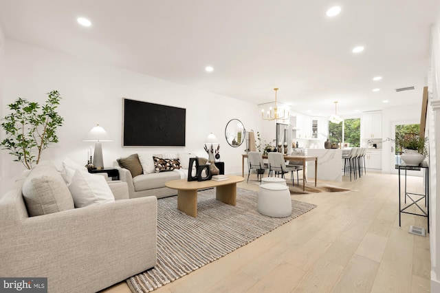 living room with light hardwood / wood-style floors and an inviting chandelier