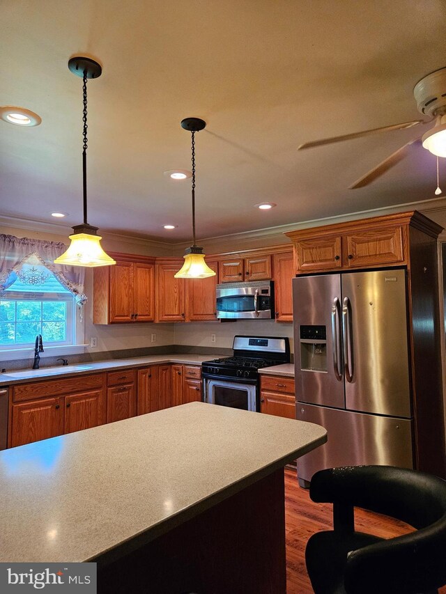 kitchen featuring ornamental molding, stainless steel appliances, sink, and hanging light fixtures