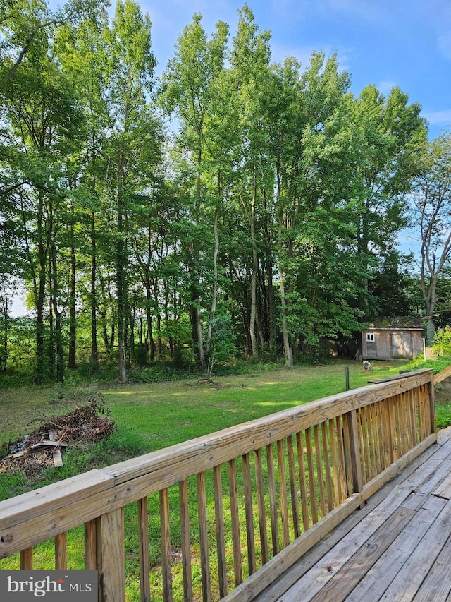 wooden deck featuring an outbuilding and a lawn