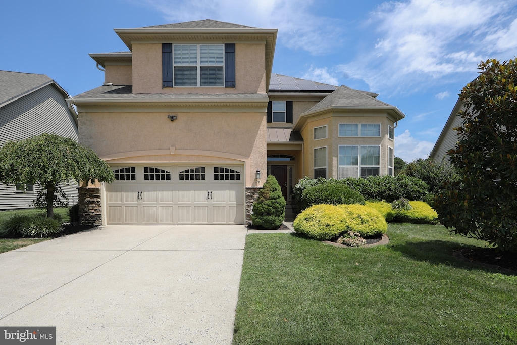 view of property featuring solar panels, a garage, and a front lawn