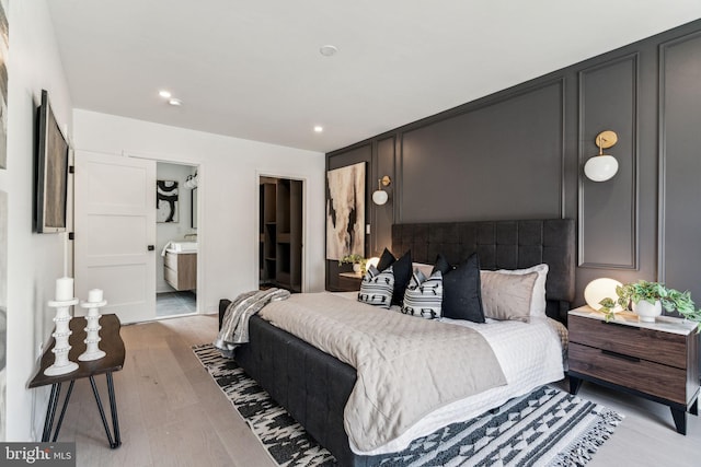 bedroom with connected bathroom and light wood-type flooring