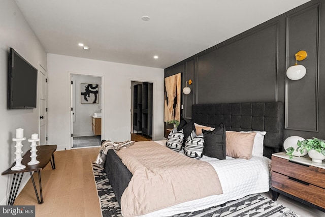 bedroom featuring ensuite bathroom and light wood-type flooring