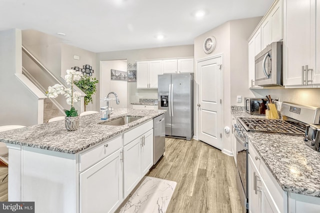 kitchen featuring white cabinetry, sink, appliances with stainless steel finishes, and an island with sink