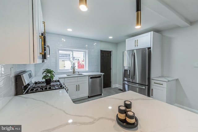 kitchen with light stone countertops, tasteful backsplash, decorative light fixtures, white cabinets, and appliances with stainless steel finishes