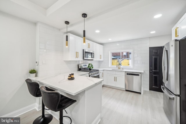 kitchen with kitchen peninsula, white cabinets, pendant lighting, and appliances with stainless steel finishes