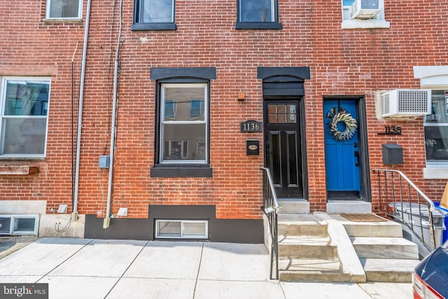 view of exterior entry featuring an AC wall unit