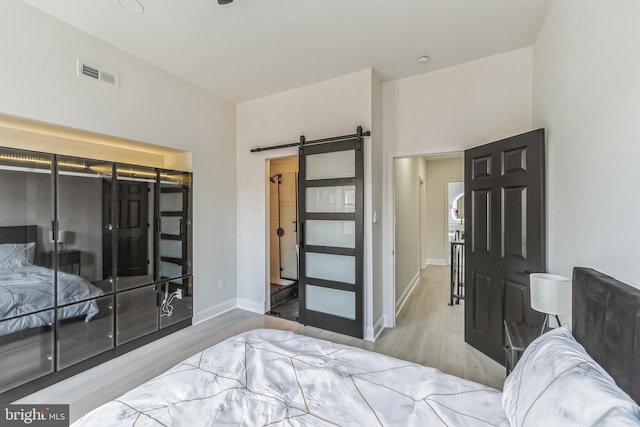 bedroom featuring a barn door and light hardwood / wood-style floors