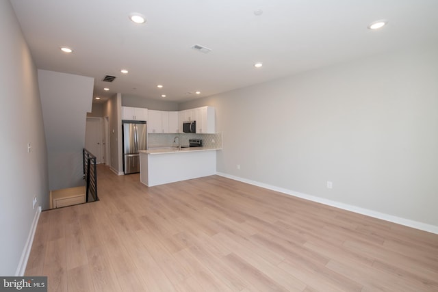 kitchen with sink, white cabinetry, light wood-type flooring, kitchen peninsula, and stainless steel appliances