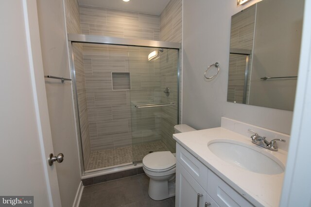 bathroom featuring vanity, a shower with shower door, tile patterned floors, and toilet