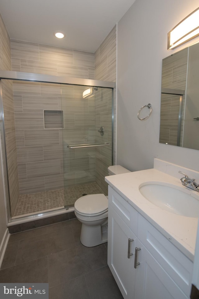 bathroom with walk in shower, vanity, toilet, and tile patterned flooring