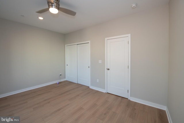 unfurnished bedroom featuring light wood-type flooring, two closets, and ceiling fan