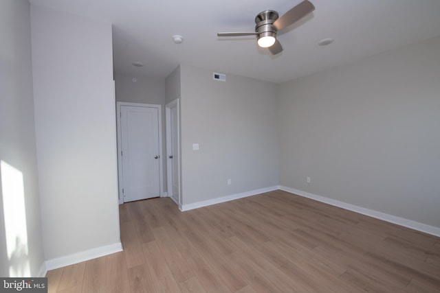 empty room with ceiling fan and light hardwood / wood-style flooring