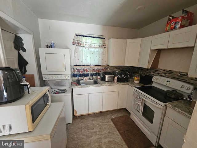 kitchen featuring sink, stacked washing maching and dryer, tasteful backsplash, white range with electric cooktop, and white cabinets