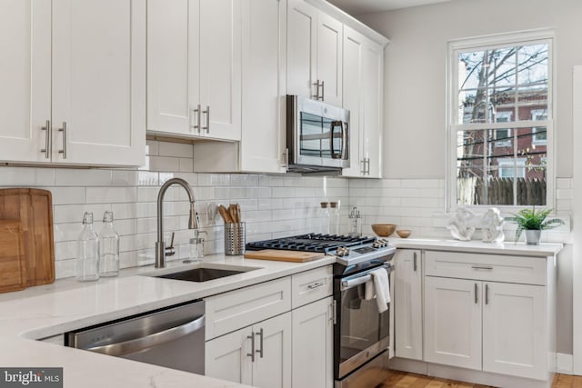 kitchen featuring light stone counters, sink, white cabinets, and appliances with stainless steel finishes