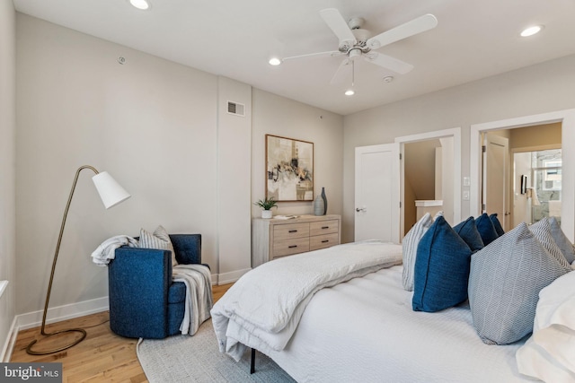 bedroom featuring ceiling fan, ensuite bath, and light wood-type flooring