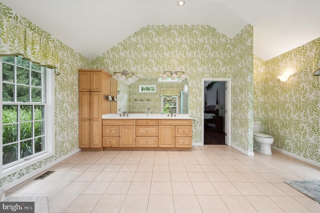 bathroom with tile patterned flooring, vanity, vaulted ceiling, and toilet