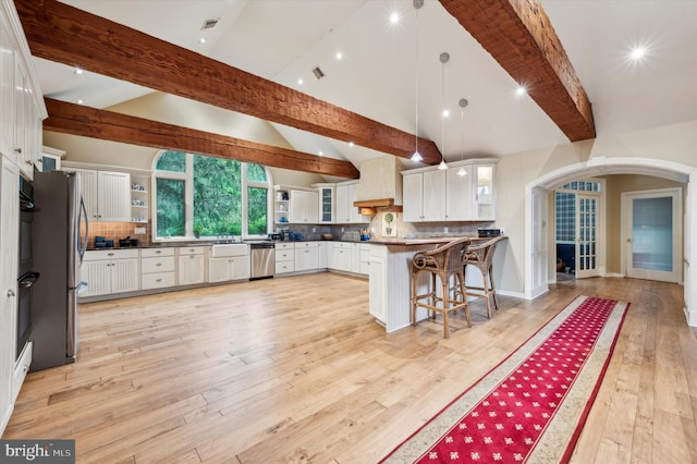 kitchen featuring a breakfast bar, hanging light fixtures, stainless steel dishwasher, decorative backsplash, and white cabinetry